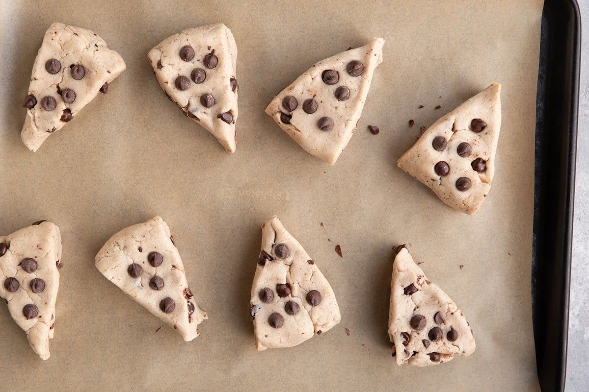 baking sheet lined with parchment paper with chocolate chip scones on top.