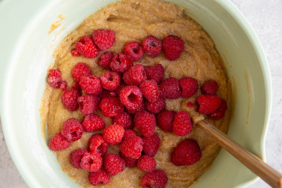 Mixing bowl full of scone dough with raspberries on top, ready to be mixed in.