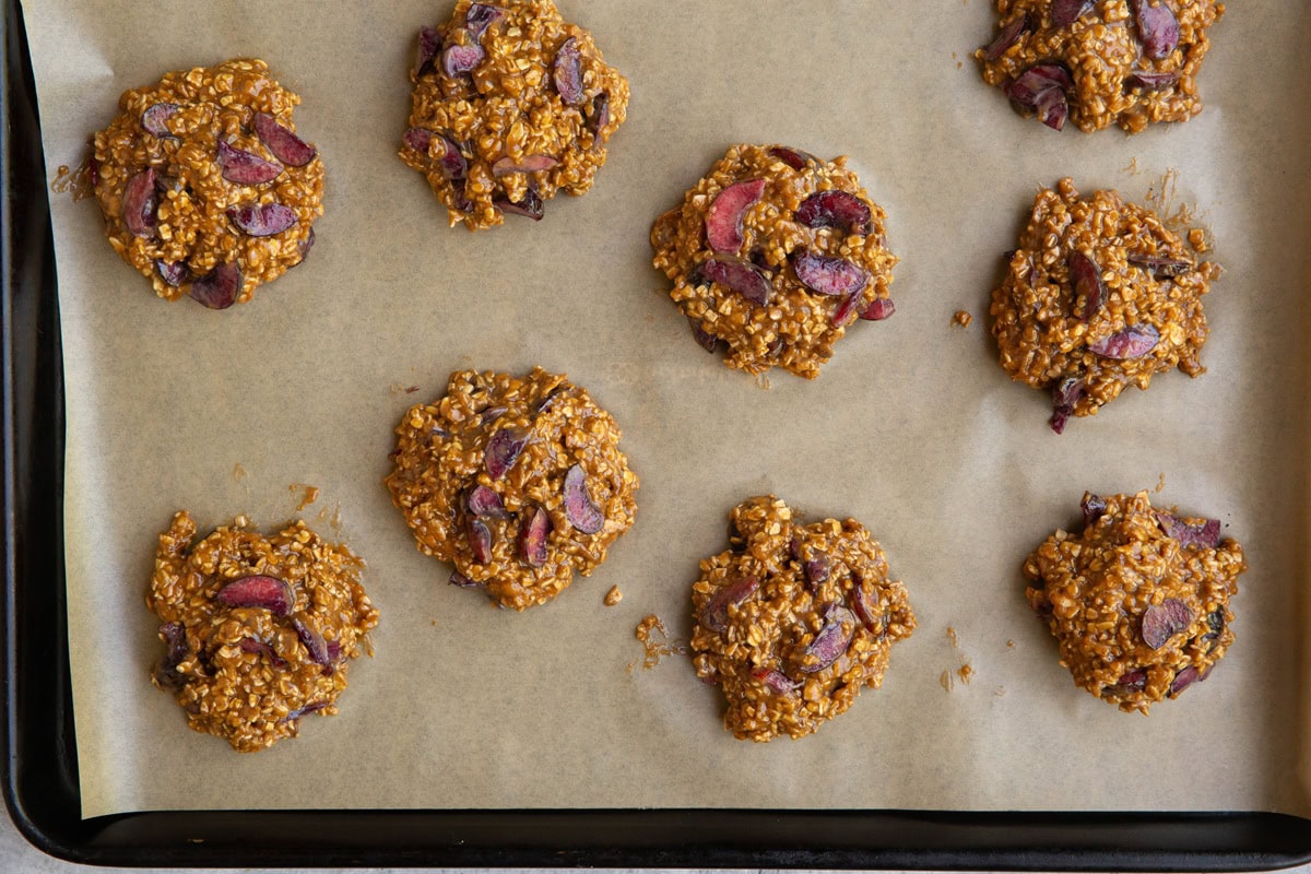 Mounds of cherry cookie dough on a parchment-lined baking sheet, ready to go into the oven.