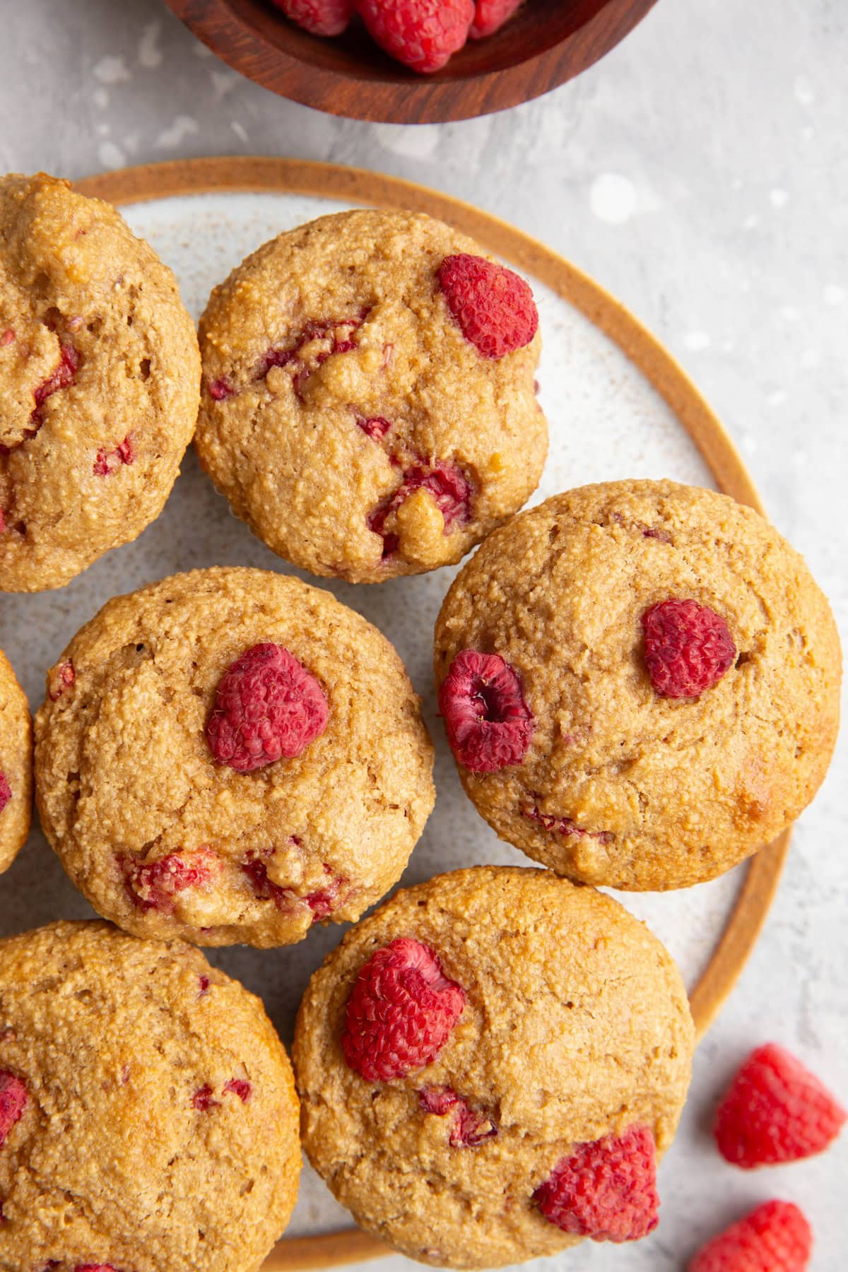 Plate with raspberry muffins and fresh raspberries to the side. Ready to serve.