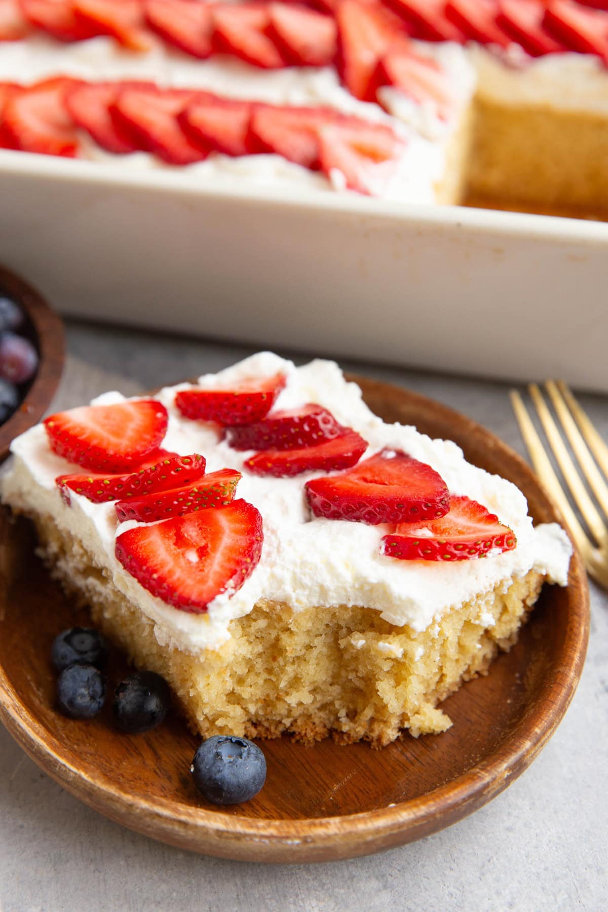 Slice of vanilla flag cake with whipped topping and a bite taken out to show the moist inside.